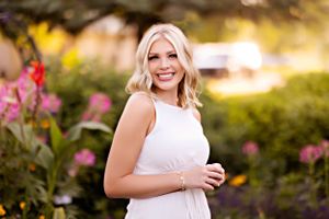 Outdoor portrait in garden with pink flowers and golden sunset lighting.