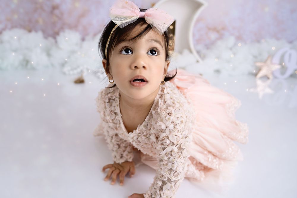 Dreamy pink birthday photoshoot with lace dress and soft lighting effects.