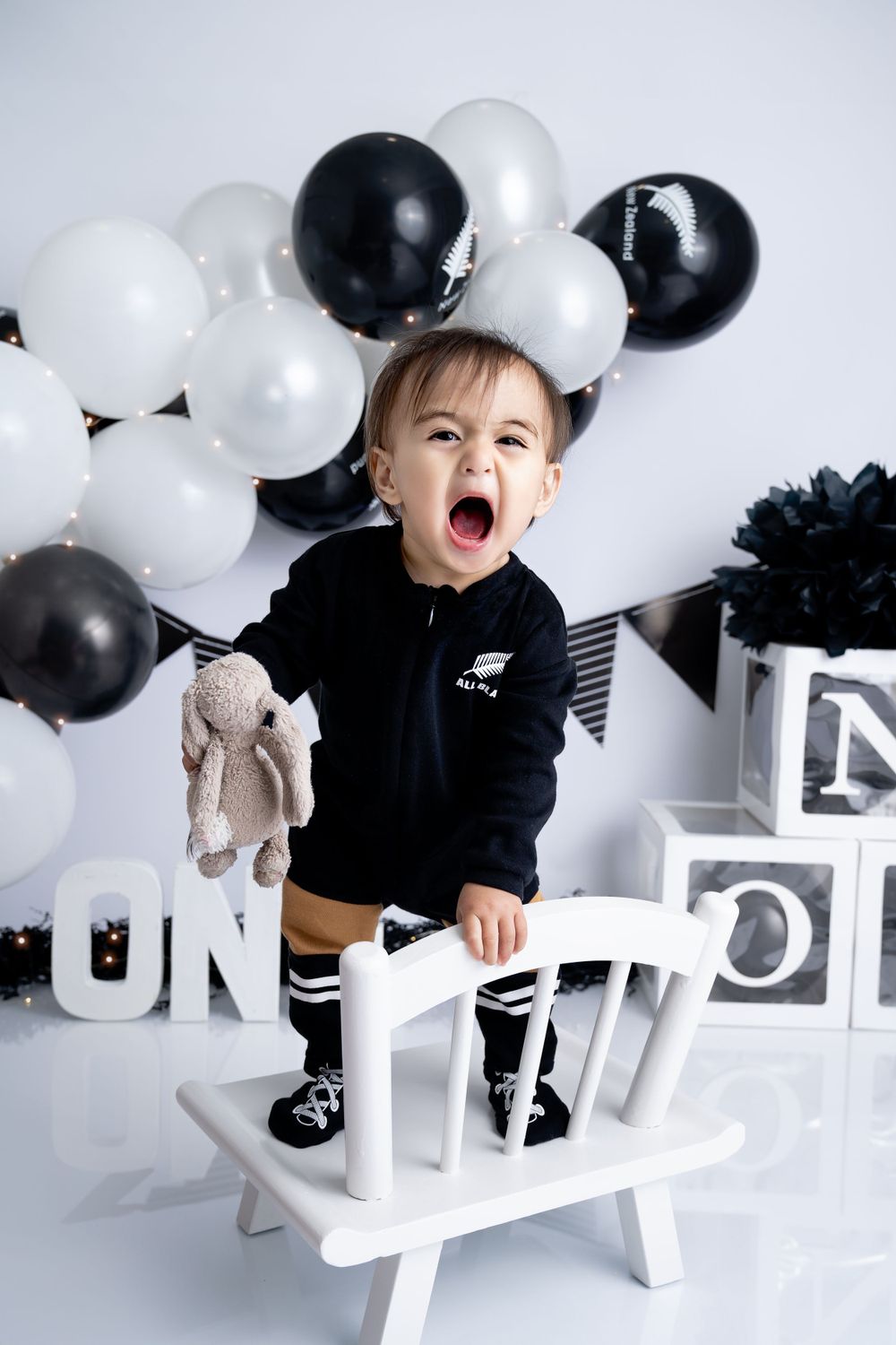 Black and white themed birthday photo session with balloons and white furniture.