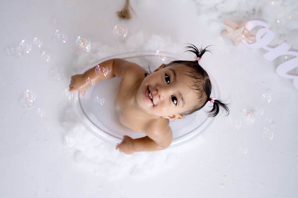 Artistic baby portrait with white clouds and sparkles in dreamy studio setting.