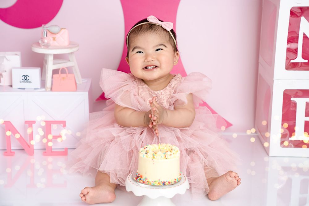 Pink themed cake smash photography session with tulle dress and party decorations.