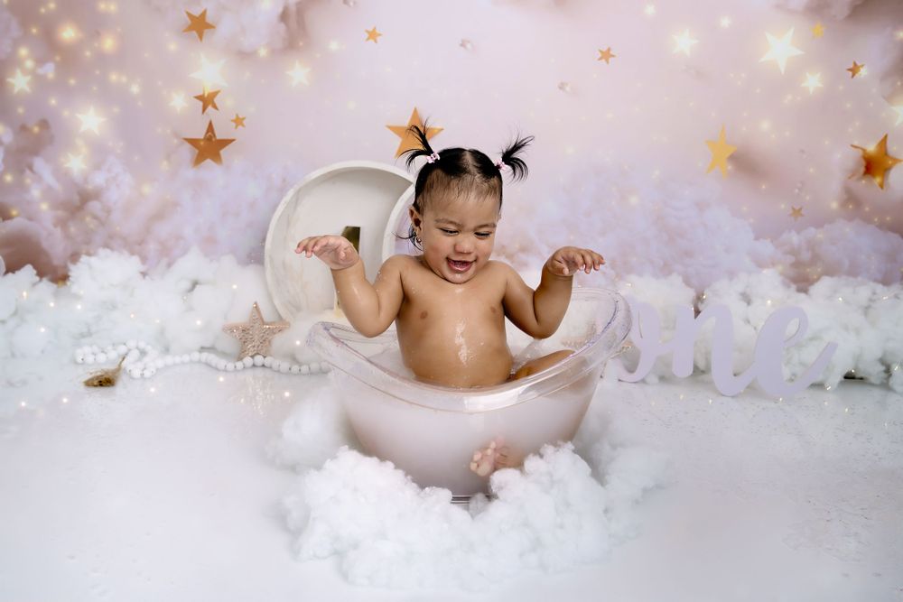 Joyful cake smash photography session with clouds and golden stars in background.