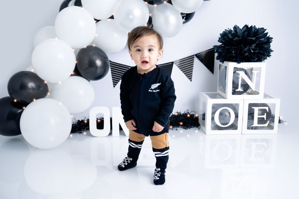 Modern black and white themed first birthday photoshoot with balloons and decor.