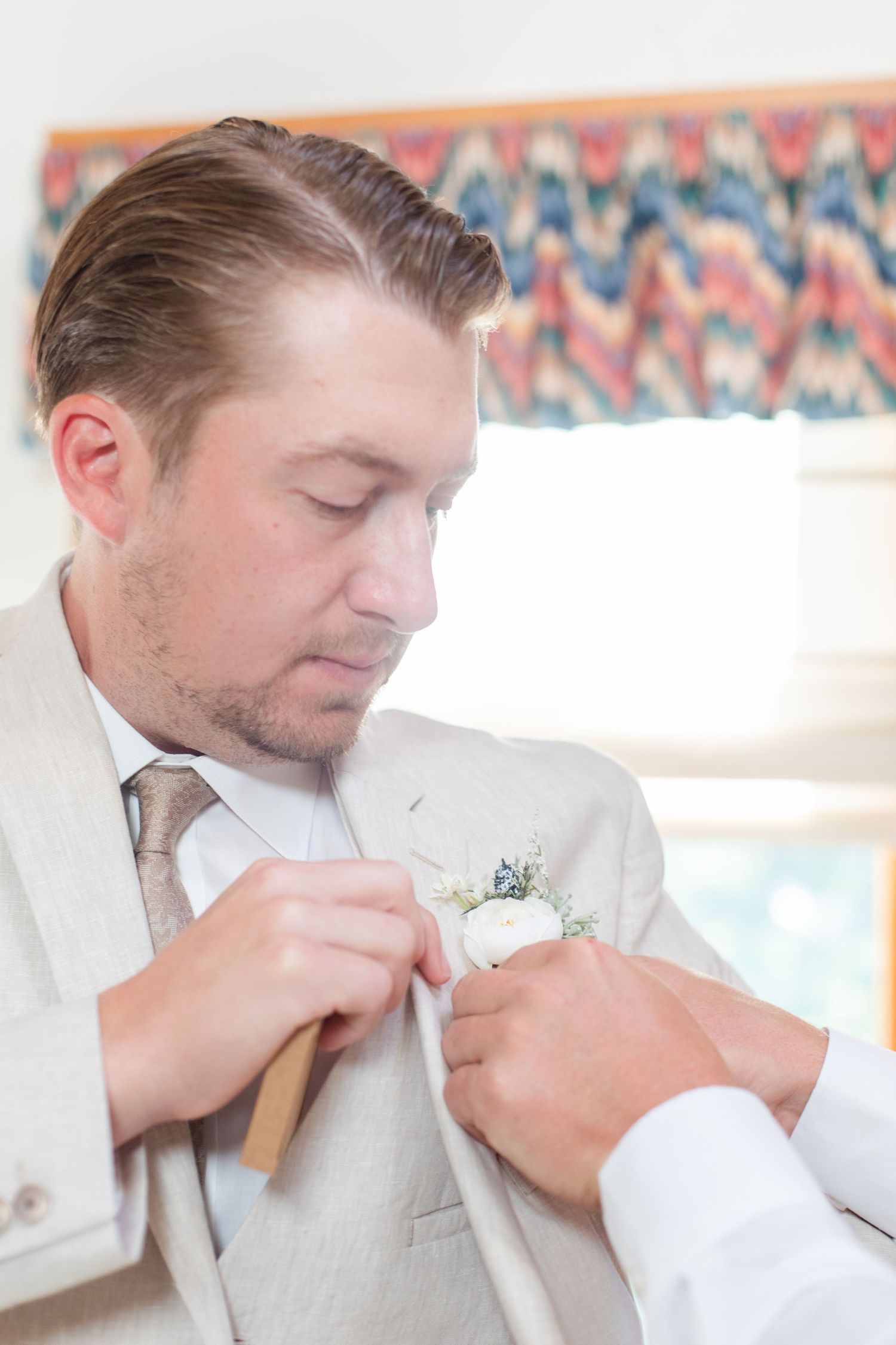 Person in light colored formal attire adjusting collar and tie.