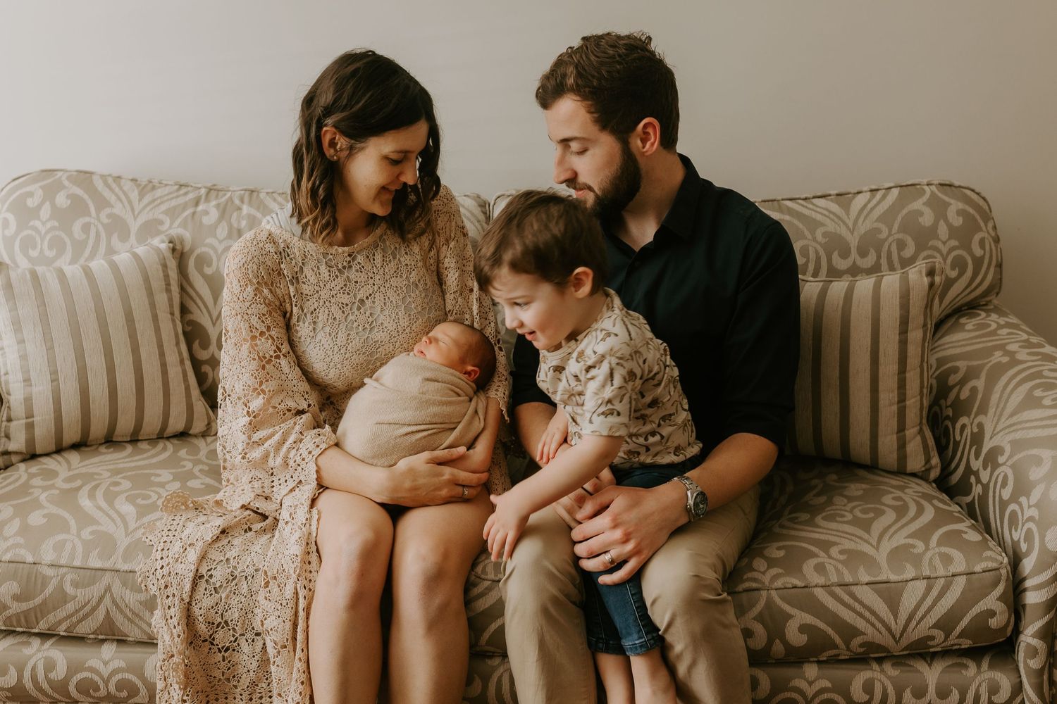 Candid lifestyle photography session with a couple and baby relaxing on textured sofa.