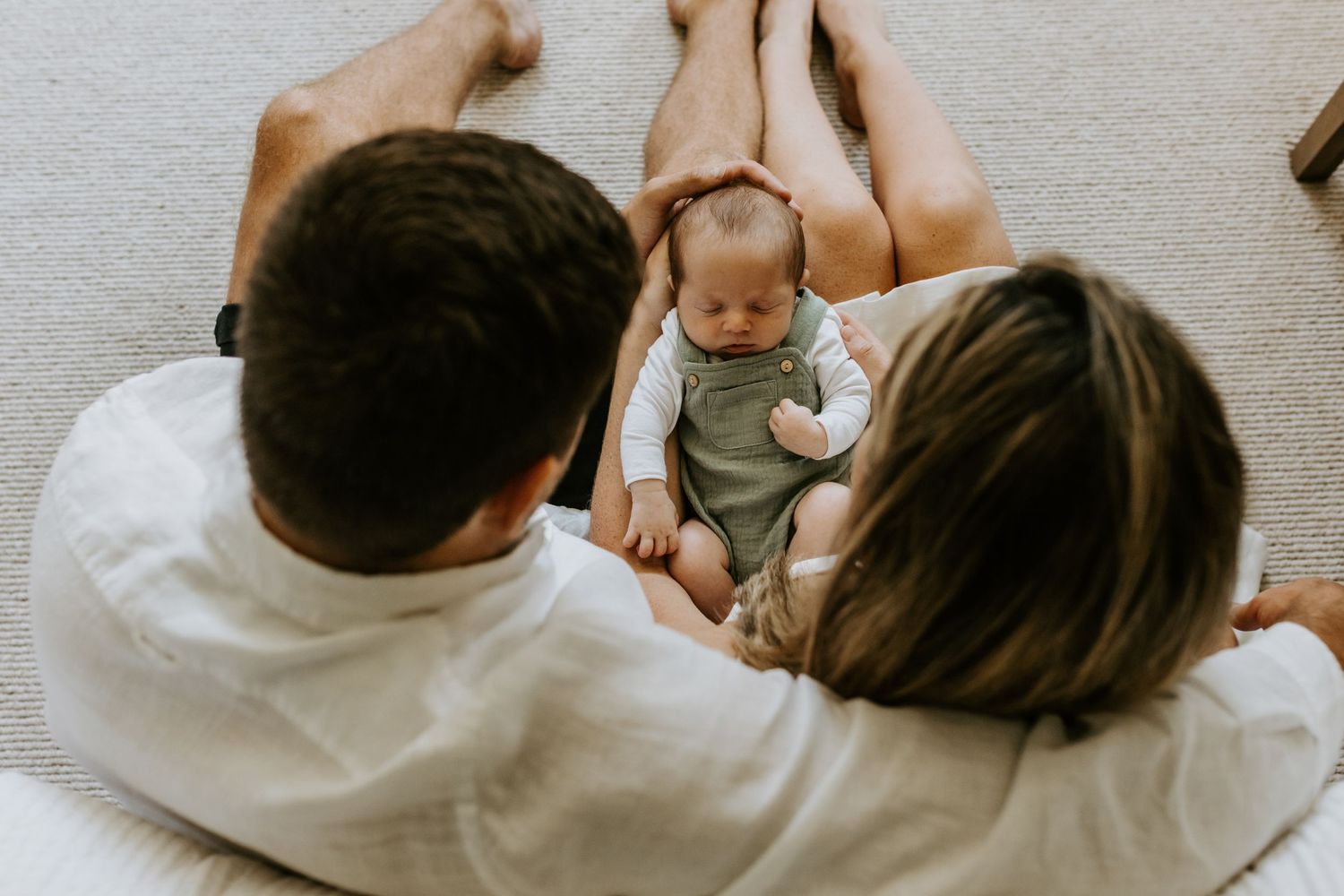 Family cuddles together on floor during intimate lifestyle photography session.