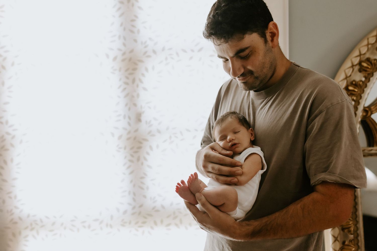 Parents cuddle their newborn baby during an intimate indoor photoshoot.