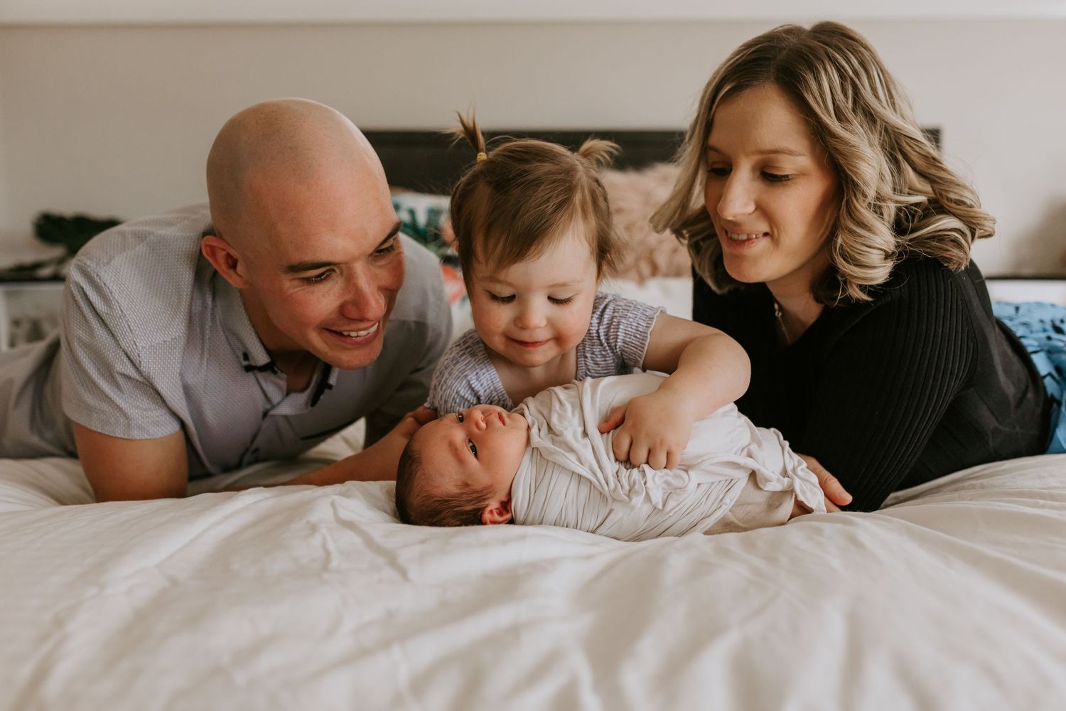 Casual family lifestyle photography session showing sweet interactions on a neutral bed.