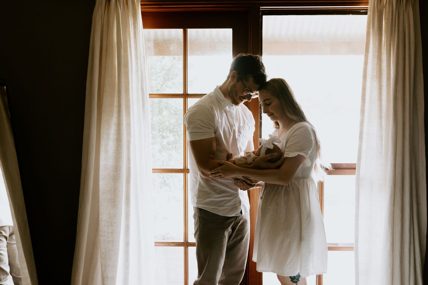 Natural light streams through window during intimate couple's photography session.