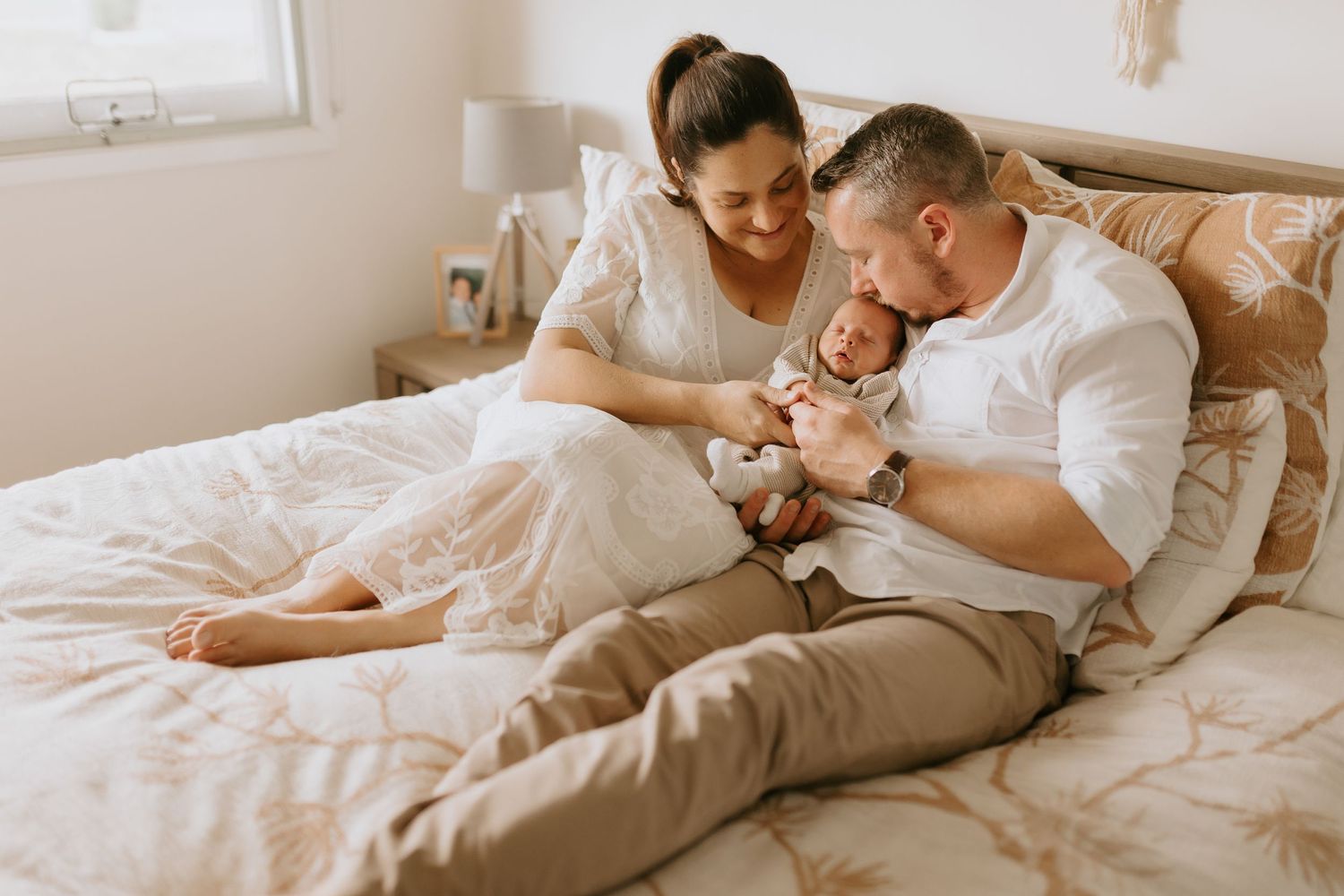 Intimate lifestyle photo on white bedding showing tender family moment.
