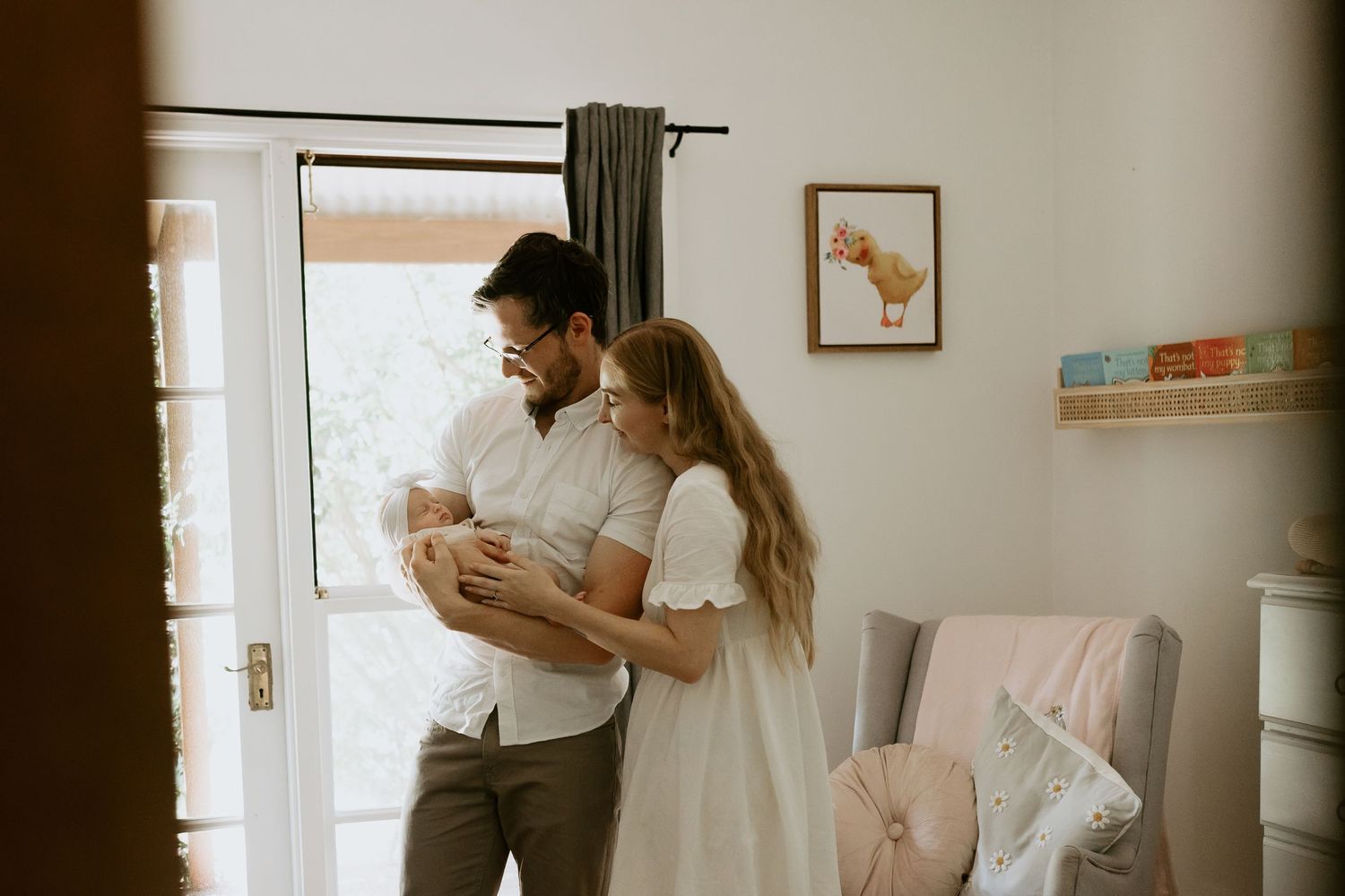 A tender family moment with parents holding their newborn baby in a warmly lit room.