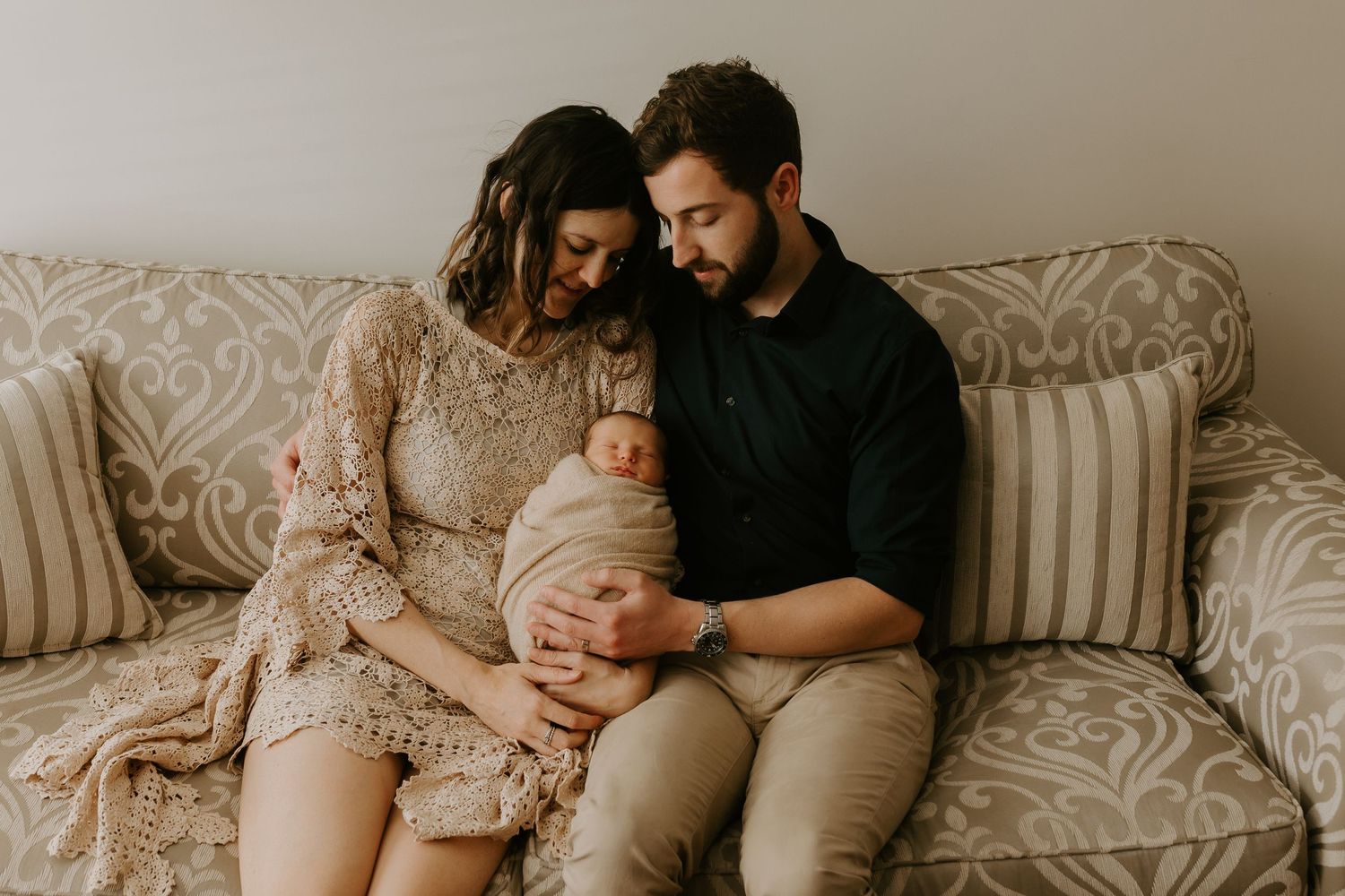 Natural light indoor family photography showing tender moments on a damask patterned couch.