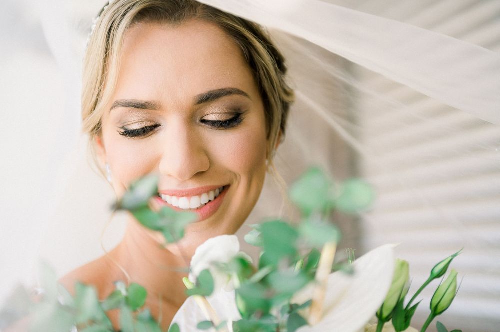 Close-up of a smiling bride with eucalyptus bouquet and veil.