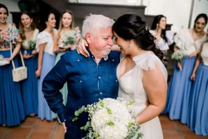 Sweet moment between bride and loved one at wedding with bridesmaids in blue dresses watching.