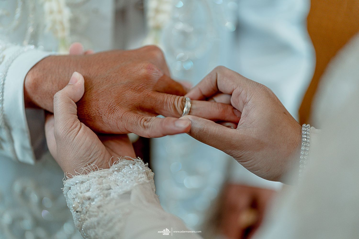 A close-up shot of hands exchanging wedding rings during a traditional ceremony.