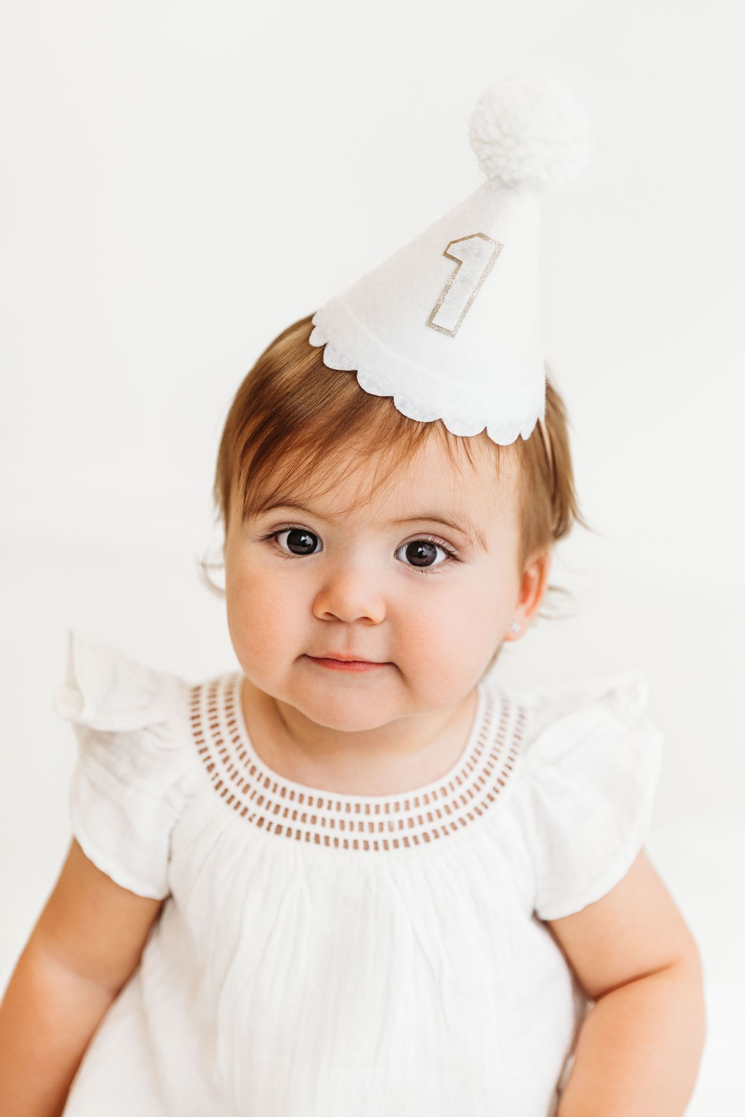 Baby girl wearing white custom made first birthday hat