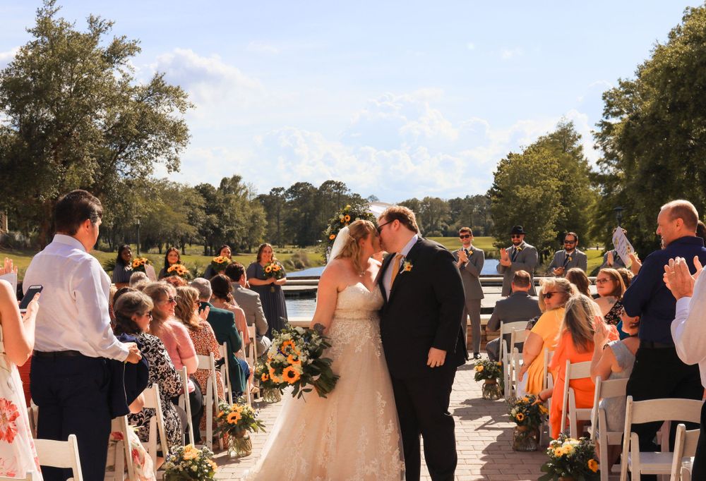 Wedding guests line a pathway as they celebrate with a couple during an outdoor ceremony.