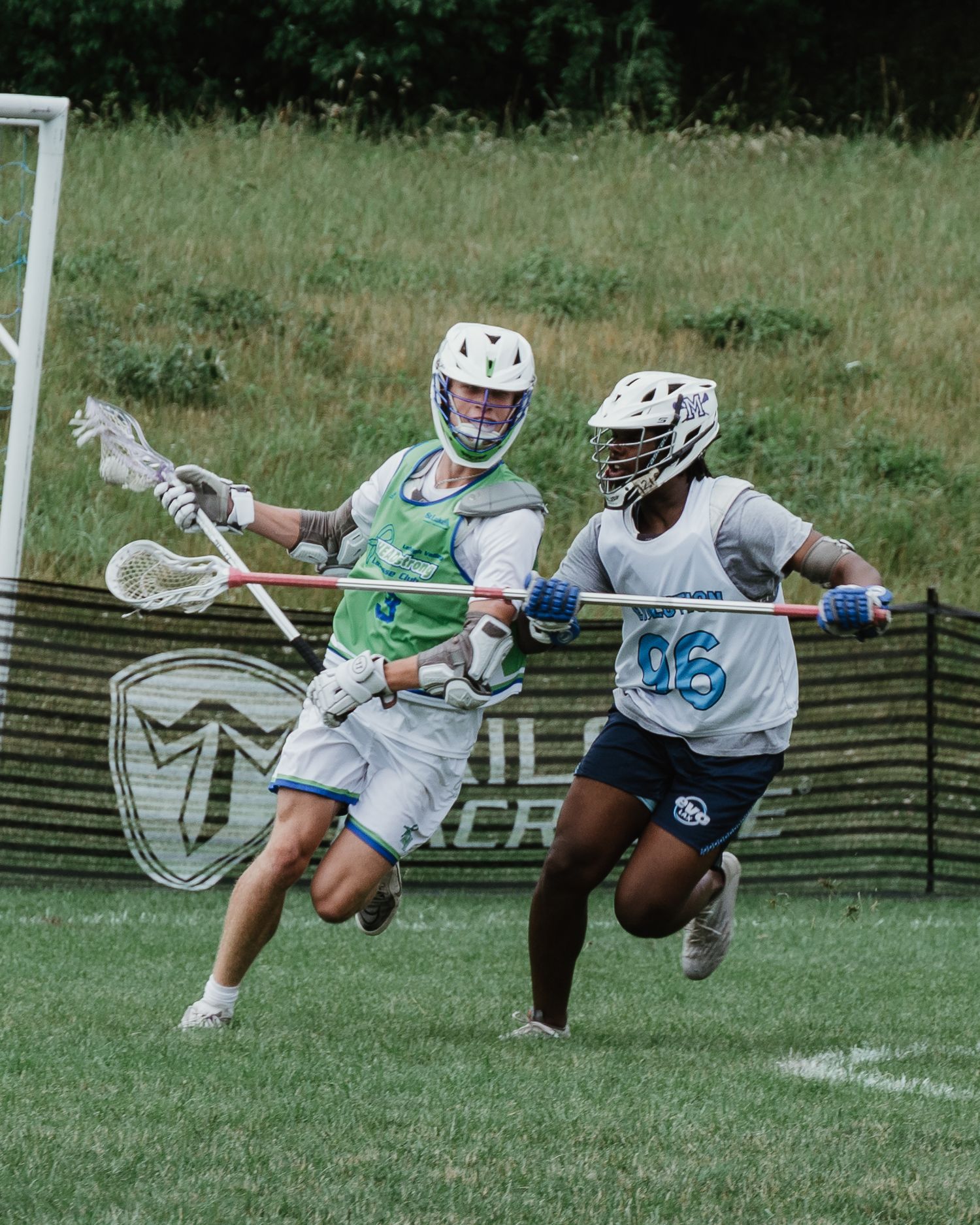 Lacrosse players dive and jump during an intense game on a grass field.