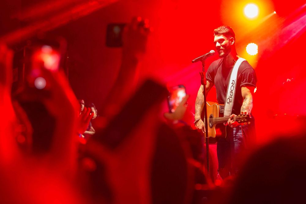 Concert performance with dramatic red stage lighting and silhouetted musicians.