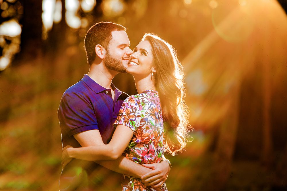 Intimate couple embracing in warm golden sunlight during outdoor photo session.