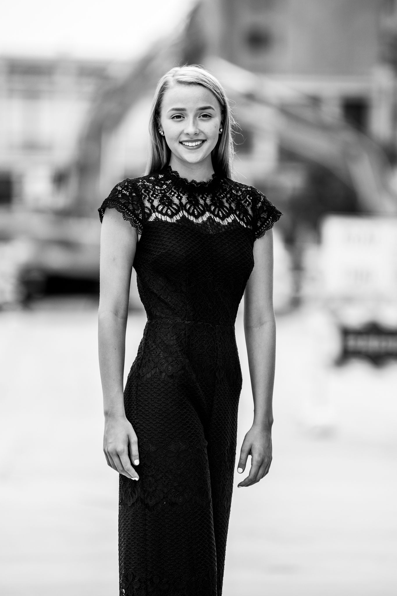 A black and white portrait of someone wearing a lace dress with a classic elegant pose.