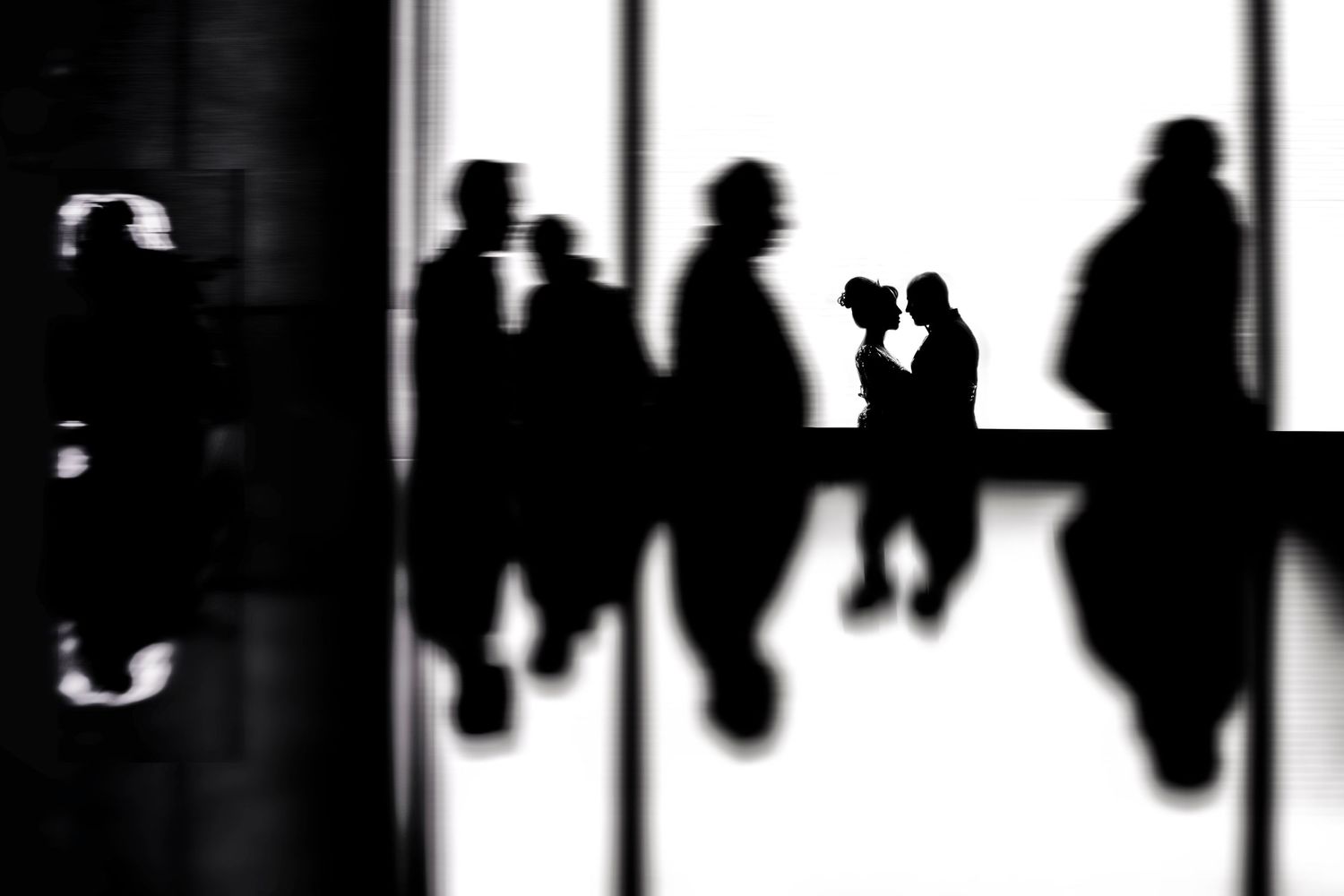Black and white silhouettes of people walking in a hallway.