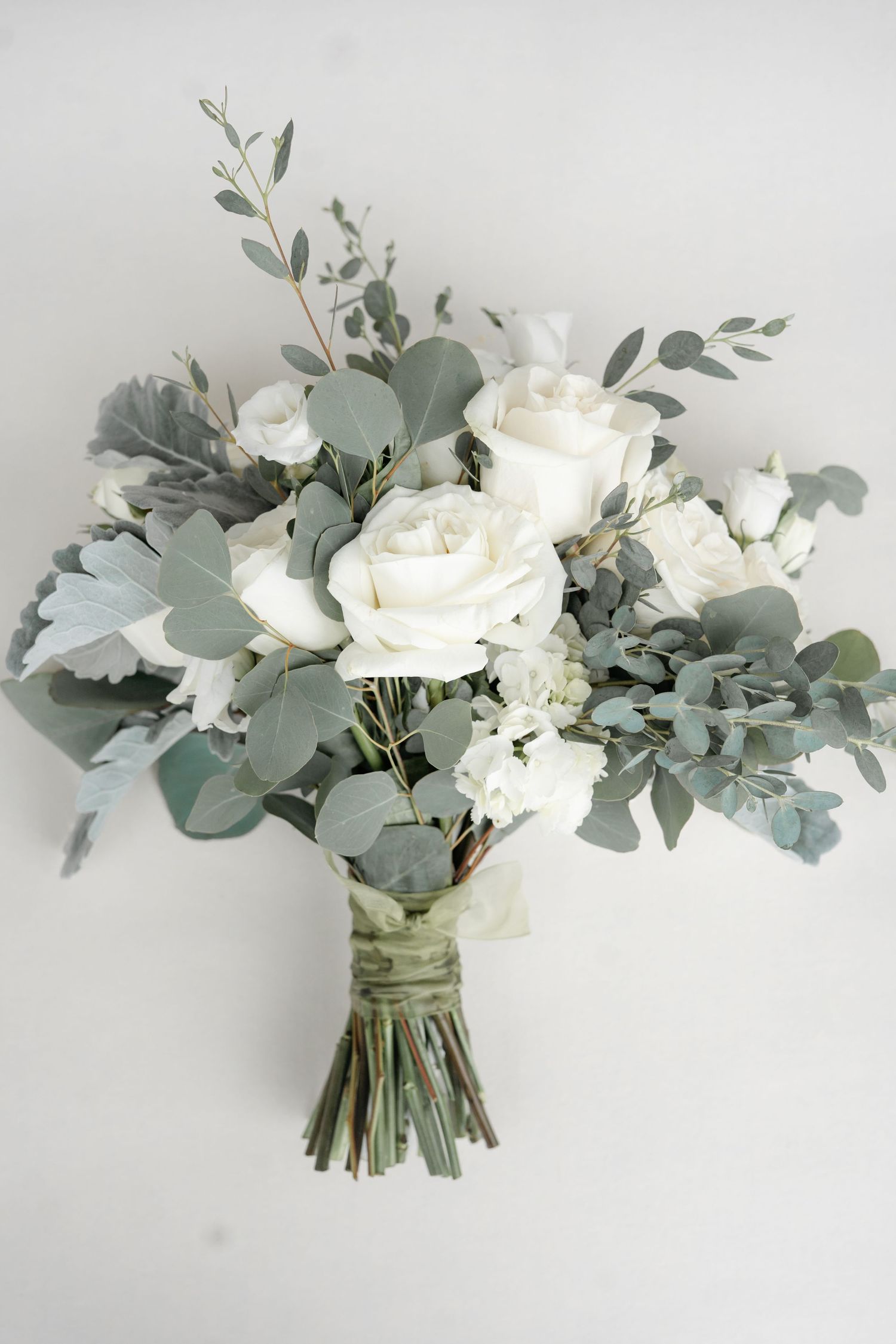 A close-up of a bridal bouquet with white roses and greenery.