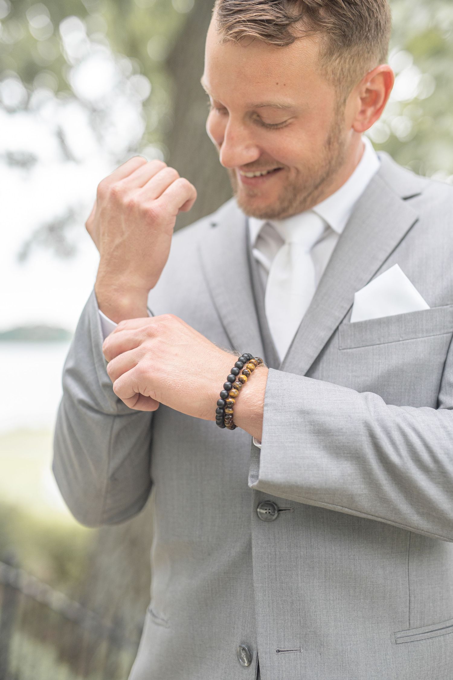 A groom adjusts his cuff while getting ready for his wedding.