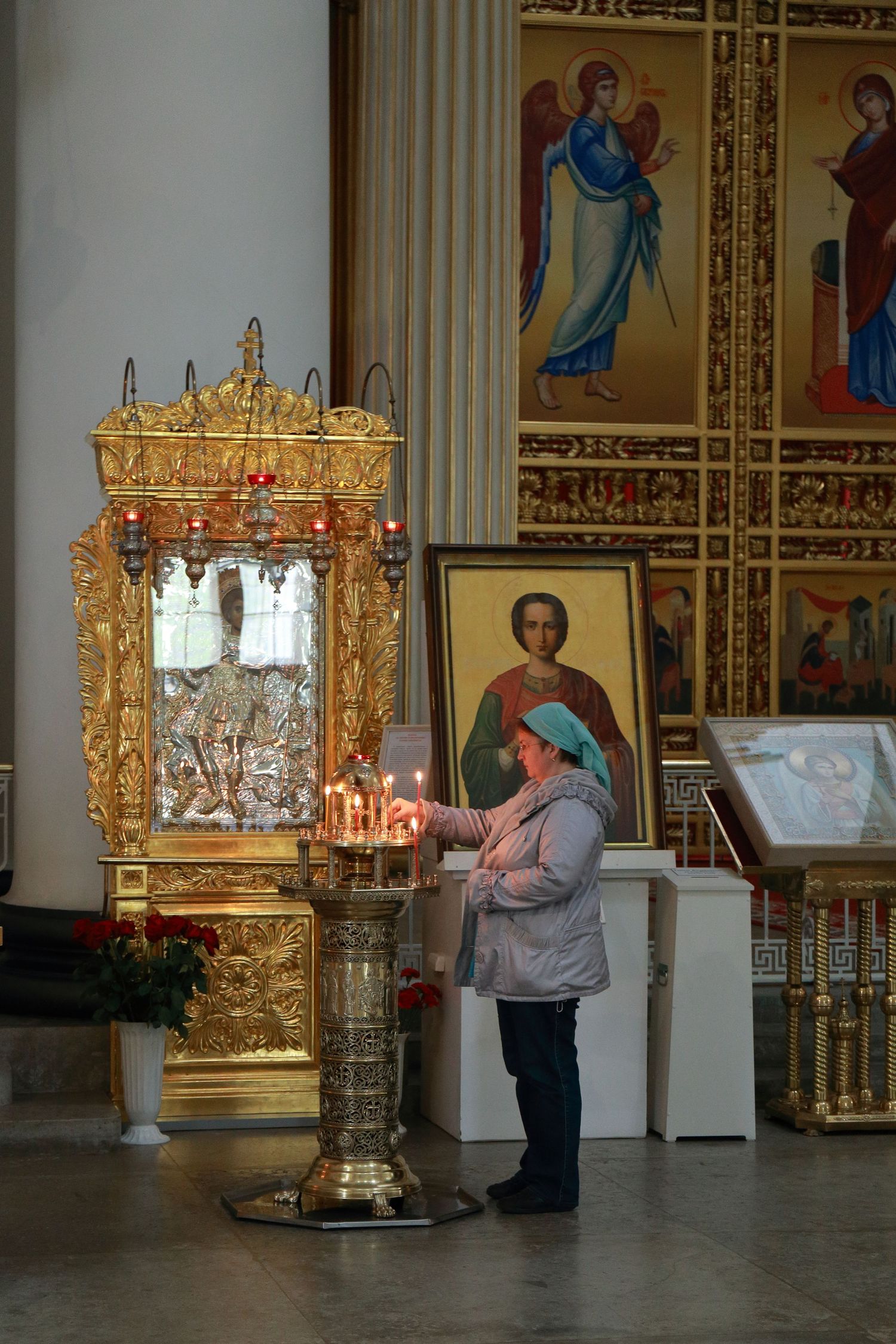 Orthodox church interior with golden altar and religious icons on decorated walls.