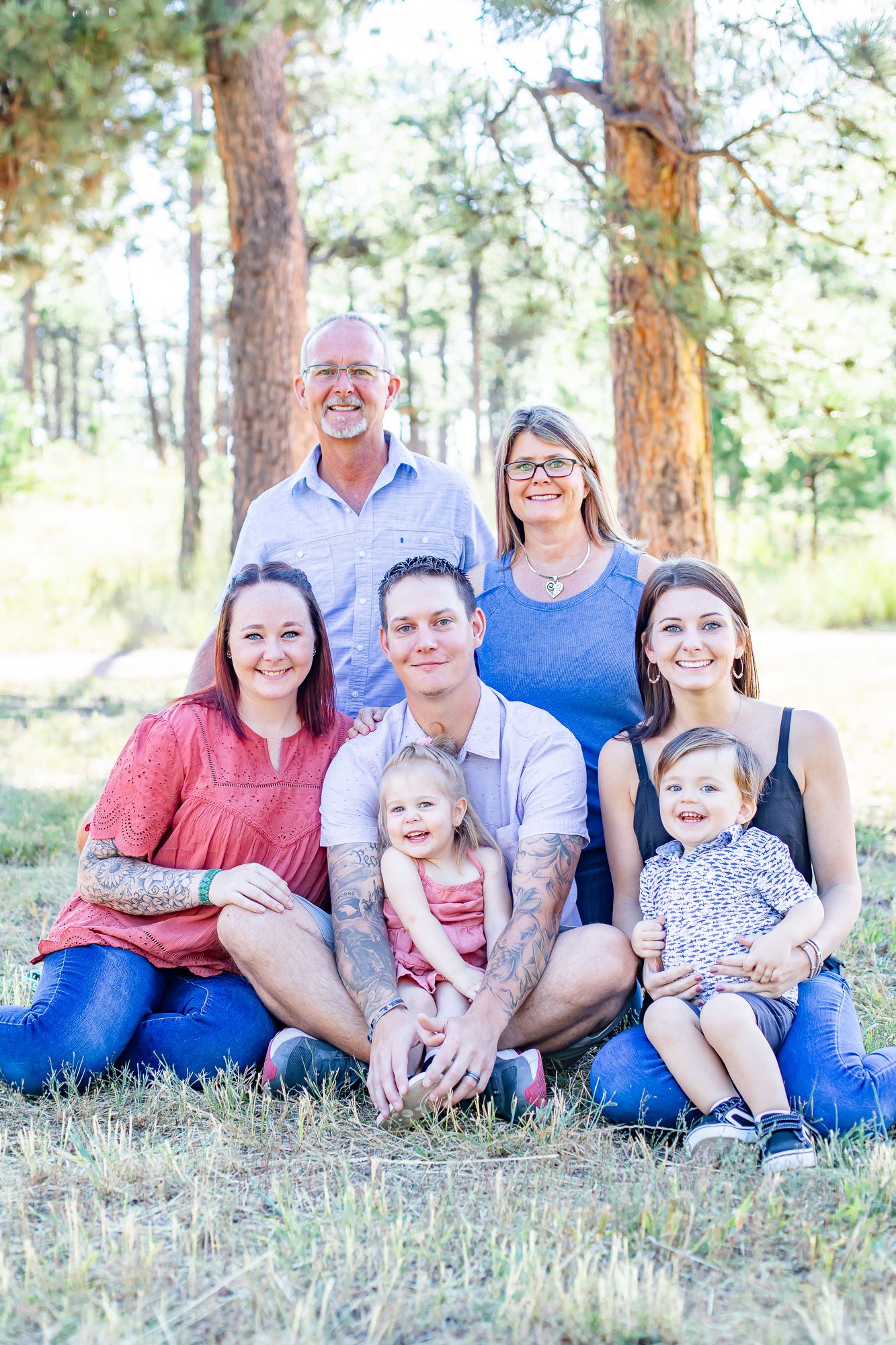 Grandparents sit with their daughters and their families together in the grass in Black Forest, Colorado.