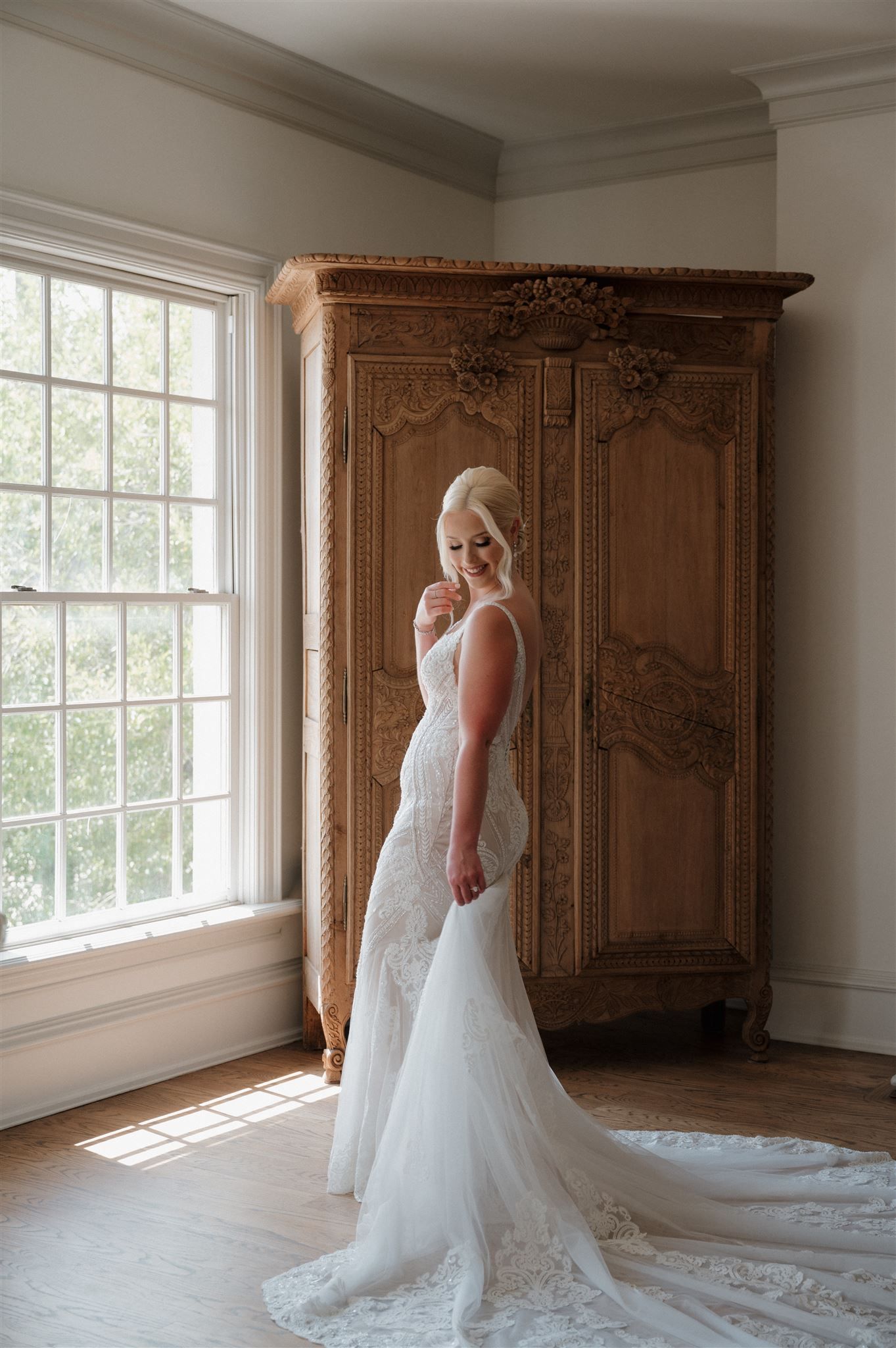 Classic bridal portrait in a room with an ornate armoire and natural window light.