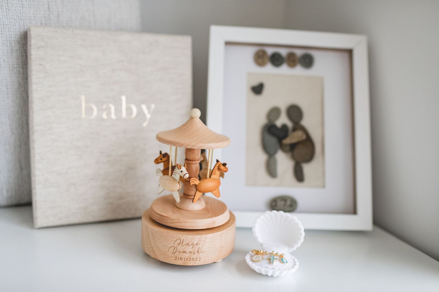 Wooden carousel music box and baby decor displayed on white shelf.