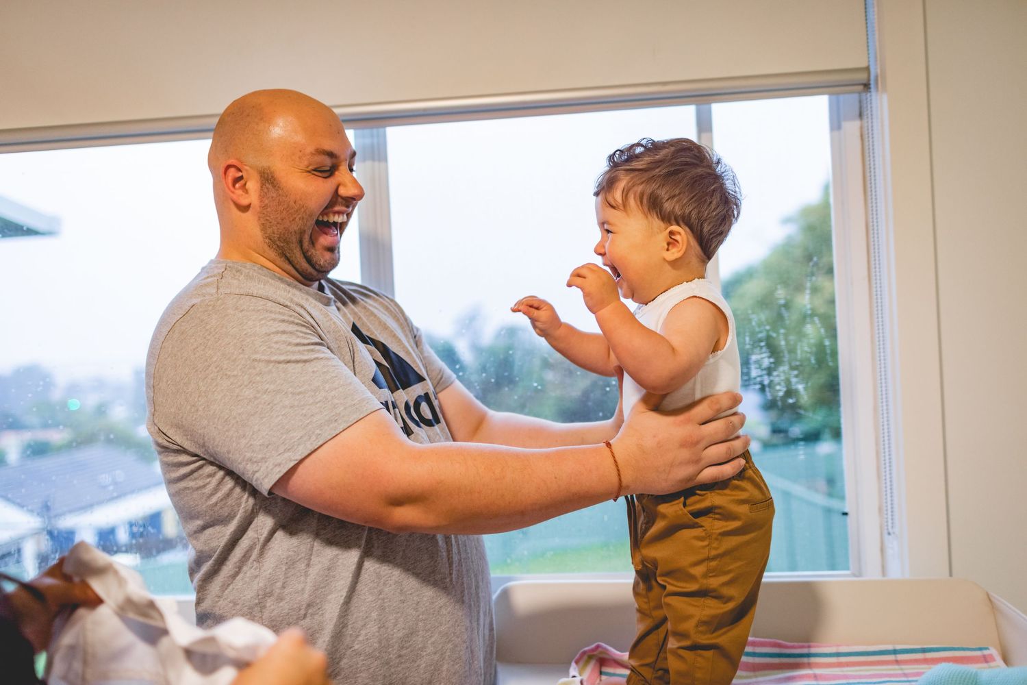 A joyful moment showing playful interaction by a window.