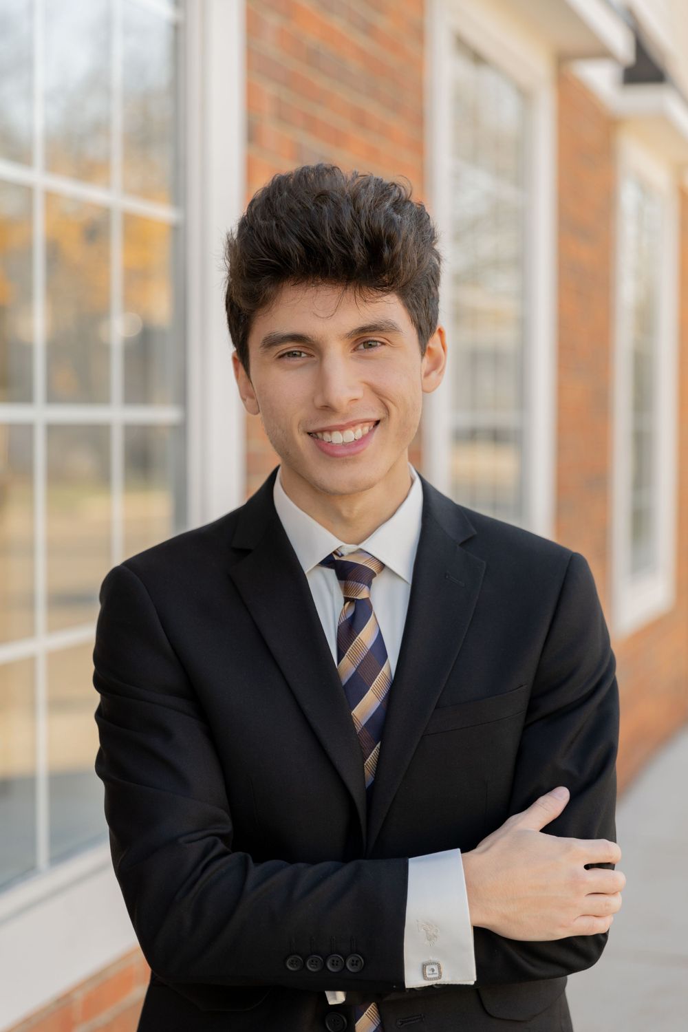 young man in a suit standing in downtow Rochester folding his arms
