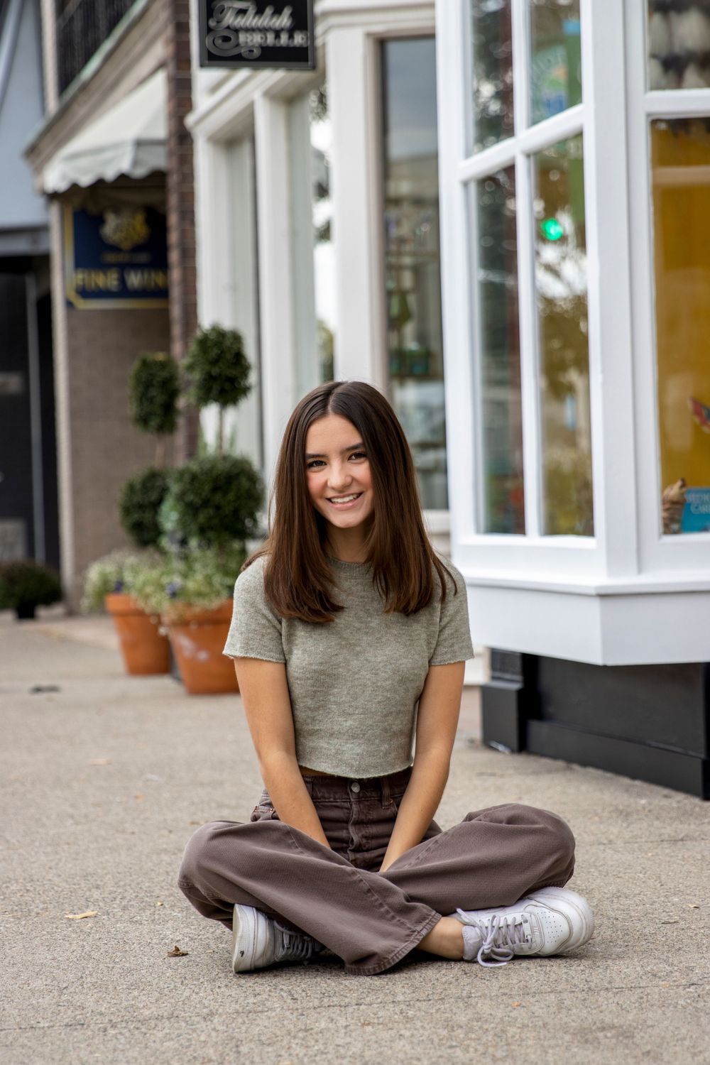 teenage girl sitting on the sidewalk in downtown Rochester michigan