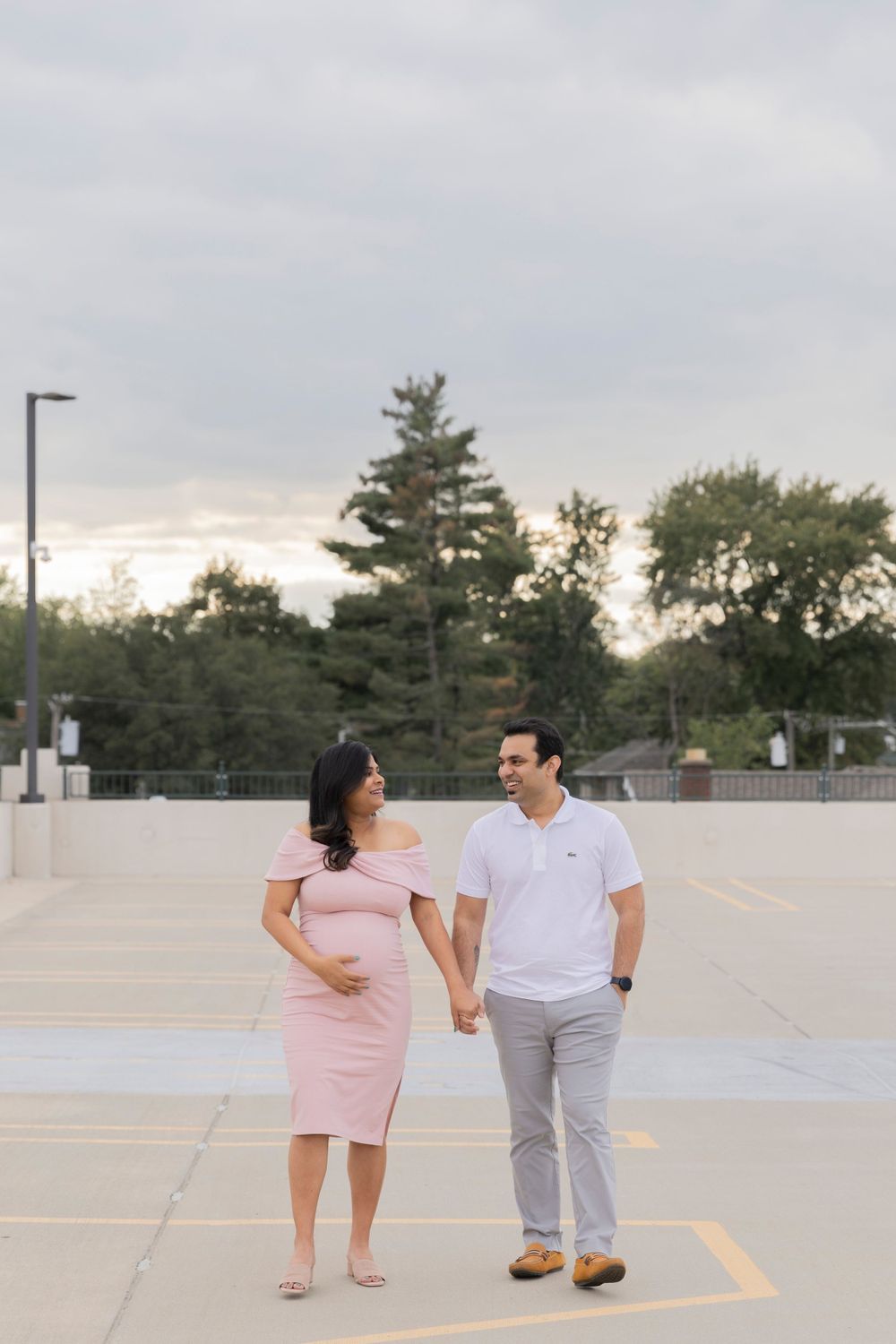 pregnant couple walking on the rooftop of a parking garage in Rochester Michigan
