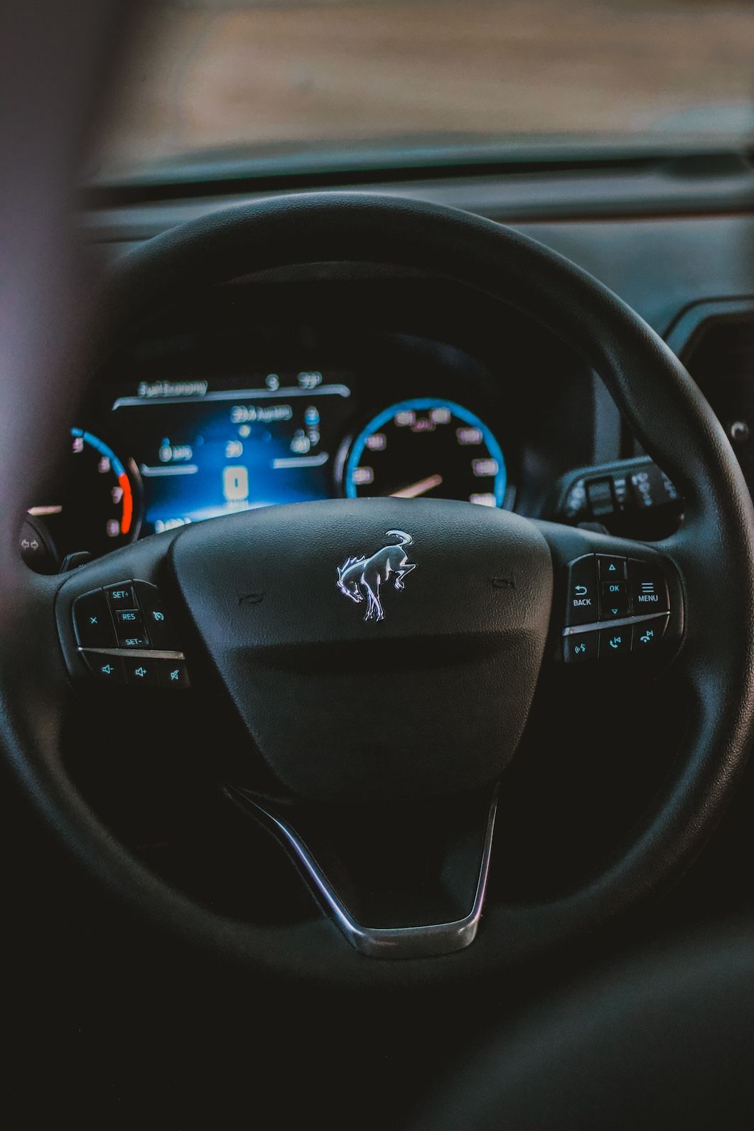 Modern car dashboard with digital display and illuminated steering wheel controls.