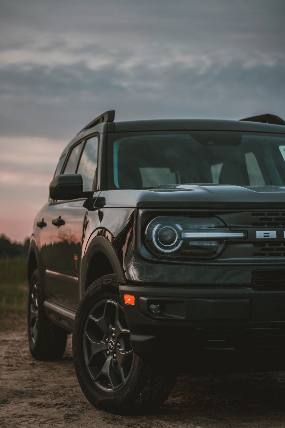 Front view of a black Ford Bronco SUV at sunset with distinctive headlight design.