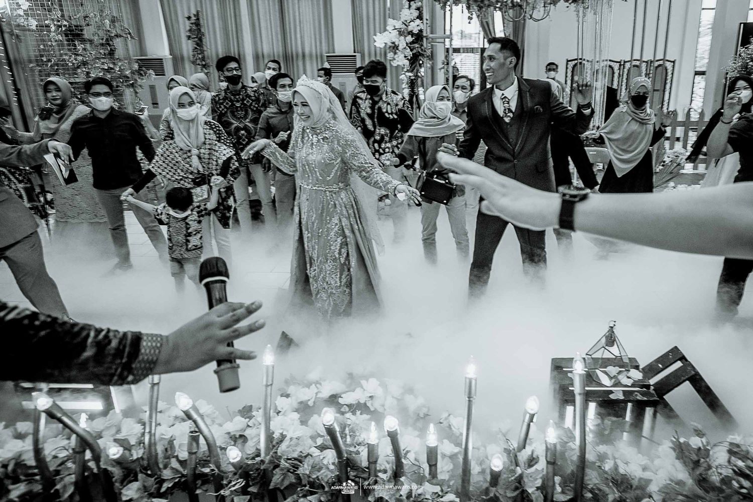 A black and white wedding celebration with fog effects and festive decorations in an indoor venue.