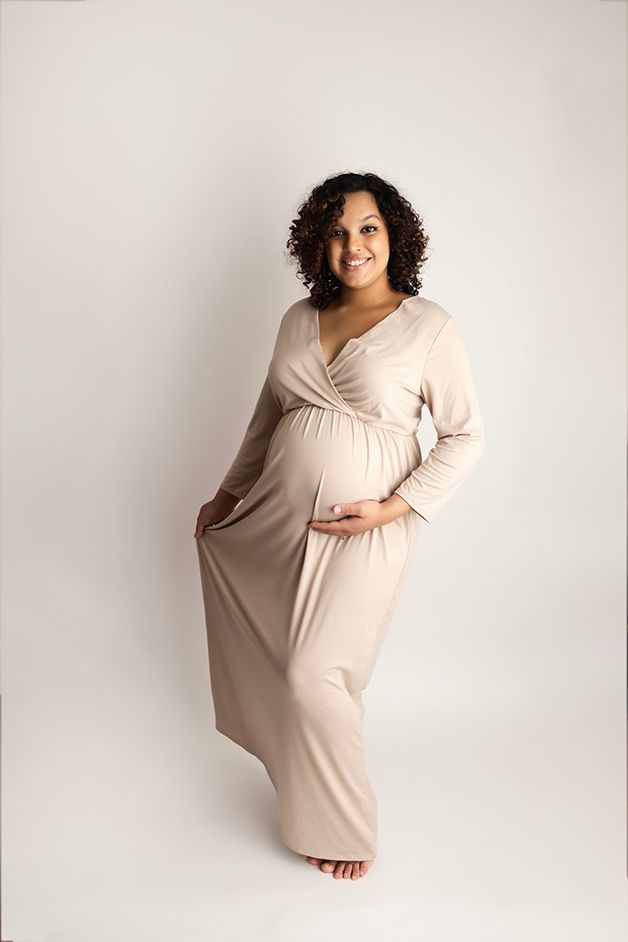 Pregnant mom in an off white dress.  She is standing on a white backdrop.