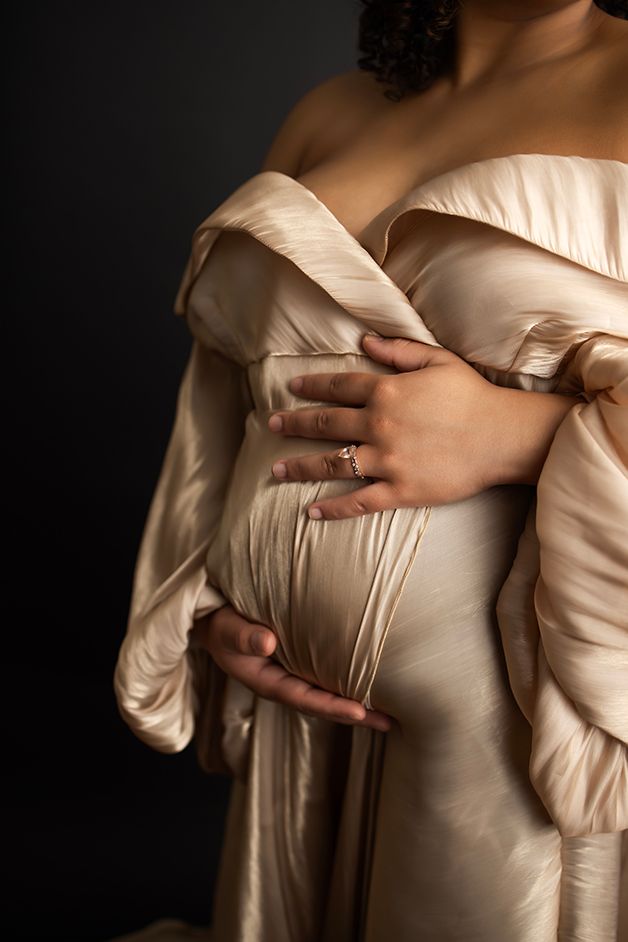 Pregnant mom's belly is the focus.  Mom is wearing a champagne maternity gown.