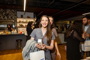 Attendee smiles while holding drink at modern industrial-style venue event.