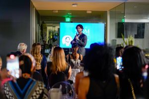Audience members record presentation on phones at evening business event.