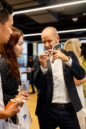 Business professional demonstrates product to interested attendees at corporate event.
