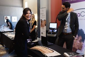 Conference attendees interact at a trade show booth with marketing materials and displays.