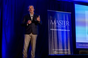 Speaker presents on stage at business conference with Master Records banner visible in blue backdrop.