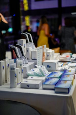 Display table showcasing white and blue skincare product containers and packaging at an event.