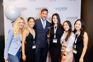 A group of professionally dressed people pose together at what appears to be a conference or business event.