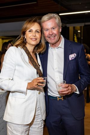 Couple in formal business attire poses with drinks at evening event.