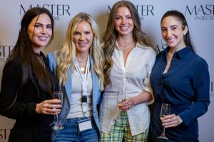 Four attendees pose and smile together at a Master event wearing business casual attire.